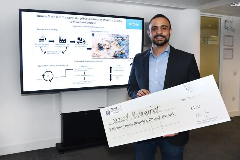 Yazeed Al-Noaimat holding a cheque beside his presentation